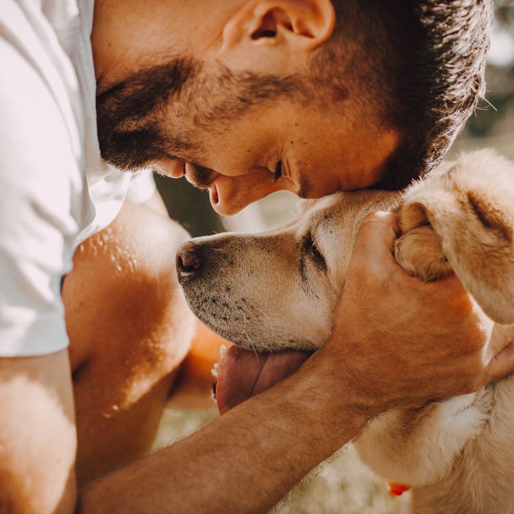 Man affectionately nuzzling dog.
